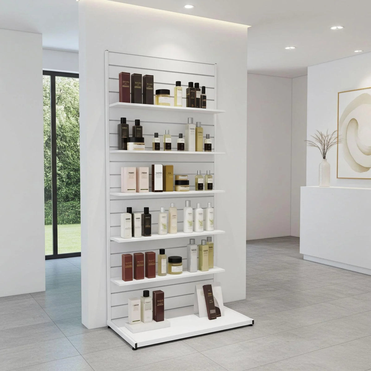 A white slatwall display shelf unit in a modern beauty salon, stocked with various skincare and cosmetic bottles and jars. The room features light gray tiled floors, white walls, and a large window on the left showing greenery outside.